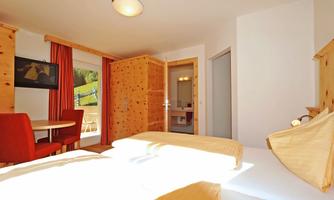 A cozy room with wood paneling and a large window. There is a table with chairs and a view of nature.