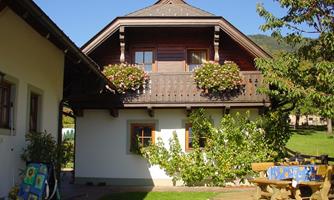 A beautiful house with a wooden balcony and blooming plants. The garden is well-maintained and invites relaxation.