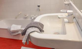A modern bathroom with a sink and a bathtub. Clean towels are placed on the sink.
