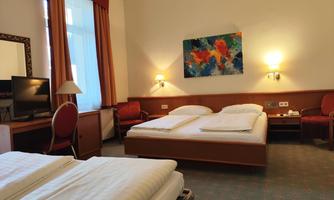 A cozy hotel room with two beds and a table. The room has a bright decor and a colorful painting on the wall.