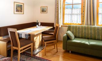 A cozy dining area with a table, chairs, and a bright couch. The windows let in a lot of light and offer a view of the beautiful surroundings.