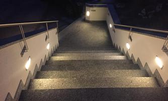 A staircase with illuminated railings at dusk. The steps are made of stone and the lights create an inviting atmosphere.