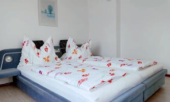 A stylish bedroom with a large double bed and colorful, floral bedspreads. The walls are bright and friendly, creating a cozy atmosphere.