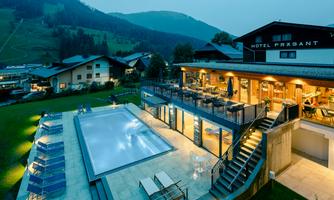 A modern hotel with a tranquil pool area and mountain views. The terrace offers comfortable seating for guests.
