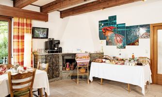 A cozy dining situation in a stylish room with wooden ceilings. There is a table with various dishes and a fireplace corner that creates an inviting atmosphere.