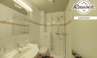 A modern bathroom with a shower, sink, and mirror. The walls are tiled in light colors, and the room feels clean and inviting.