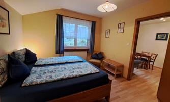 A cozy bedroom with a double bed and luggage rack. The room has a large window that lets in plenty of light.