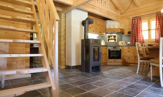 A cozy wooden apartment with stairs, kitchen, and dining area. The decor is rustic and inviting.