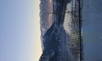 A picturesque winter landscape with snow-covered mountains and a serene lake. The sky is clear, and the landscape is bathed in soft colors.