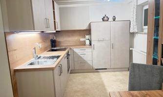A modern kitchen with wood decor and bright cabinets. The space is well-lit and includes a sink, a stove, and a refrigerator.