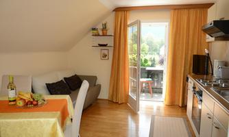 A bright and cheerful apartment with a kitchenette and a dining area. Large windows provide plenty of daylight and a view of the balcony.
