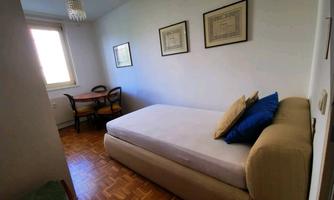 A bright room with a daybed and two pictures on the wall. A small table with chairs is in the corner.