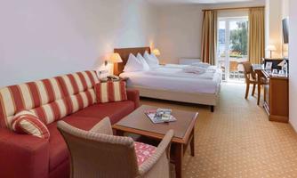 A bright and comfortable room with a double bed and a cozy sofa.  
Large windows provide daylight and a view of the outdoor area.