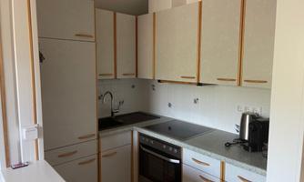 A modern kitchen unit with bright cabinets and a stove. The kitchen is well-equipped and tidy.