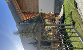 A charming wooden house in the mountains. The garden is well-kept and surrounded by a beautiful fence.