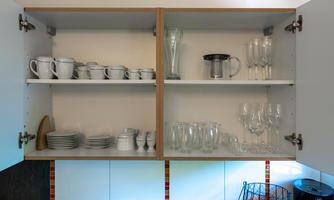 A kitchen cabinet with clean cups, plates, and glasses. The shelves are neat and well organized.