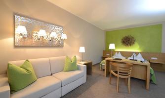 A modern room with a comfortable sofa and natural green tones. The lighting and furniture create an inviting atmosphere.
