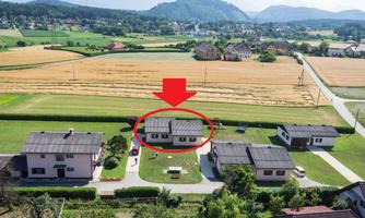 An aerial shot of several residential houses in a rural setting. In the background, mountains and fields can be seen.