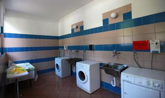A washroom with two washing machines and a sink. The walls are designed with blue and beige tiles.