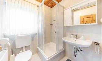 A modern bathroom with a separate shower, sink, and toilet. Large windows allow for plenty of daylight.