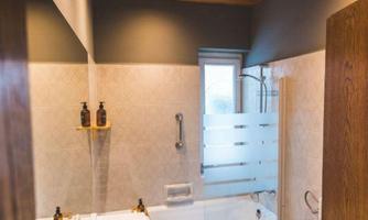 A modern bathroom with a bathtub and sink. The wooden wall and ceiling give the room a warm atmosphere.