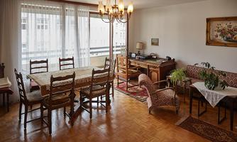 A bright living room with a large dining table and chairs. Against the wall is a desk and a cozy seating area.