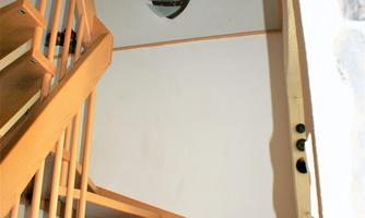 A staircase with bright wooden steps and a wall with a painting. Above the stairs hangs a decoration with sunflowers.
