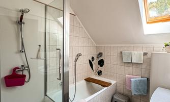 A modern bathroom with a shower and bathtub. There are bright tiles and large windows that let in natural light.