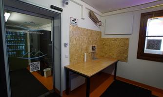 A modern room with wood paneling and a table. The walls are light, and there is a clear view of the entrance area.
