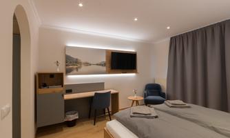 A modern hotel room with a double bed, a desk, and a television. The walls are painted in neutral colors and a curtain provides privacy.