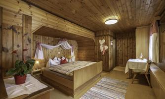 A cozy bedroom with wood paneling and a large bed. A small seating area with a table and chairs is also available.