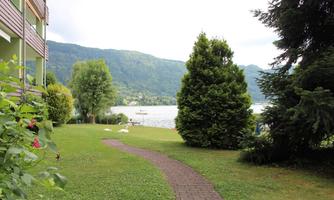A well-maintained garden with a path that leads to the water. In the background, there are mountains and a calm lake.