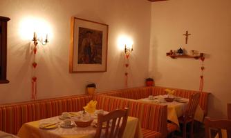 A cozy restaurant with wooden interiors and colorful benches. The tables are set with dishes and a yellow tablecloth.