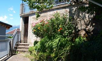A small garden landscape with colorful flowers in front of a building. In the background, a blue sky is visible.
