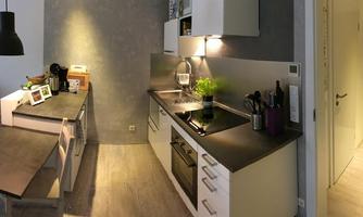 A modern kitchen with a dark countertop and light cabinets. The space is designed to be both functional and stylish, with a cozy dining area.
