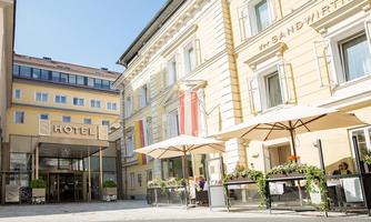 A stylish hotel with an inviting facade and terraces. The surroundings are brightly lit and designed to be friendly.