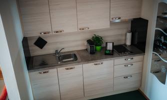 A modern kitchen with wooden surfaces and a practical arrangement. Green plants and kitchen appliances are placed on the countertop.