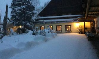 A snowy courtyard with a illuminated building. The scene conveys a tranquil winter atmosphere.