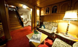 A cozy living room with a wooden interior and a red carpet.  
On the table, there is a small table with flowers, and there is a staircase in the background.