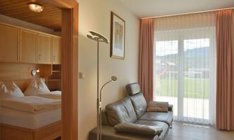 A bright and cozy apartment with a living area and a sleeping space. Large windows provide plenty of daylight and a view outside.