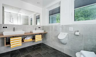 A modern bathroom with two sinks and bright tiles. Large windows provide plenty of daylight.