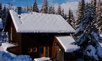 A cozy house in winter, surrounded by snow-covered trees. The sky is clear and the atmosphere is peaceful.