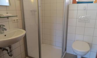 A modern bathroom with a shower, a sink, and a toilet. The walls are brightly tiled and the space appears clean and inviting.