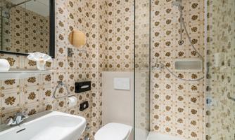 A modern bathroom with a bright tile pattern and clean lines. It includes a shower, a sink, and a toilet.