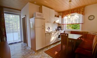 A cozy kitchen with a modern design and a dining area. Large windows provide plenty of daylight and a view of the outdoors.