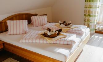 A cozy bedroom with a double bed and striped pillows. Decorative towels are placed on the beds.