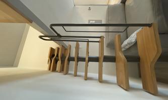 A modern spiral staircase made of wood leads to an upper area. The room is bright and furnished in a minimalist style.
