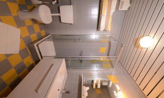 A modern bathroom with a shower and bright yellow accents. It features a toilet and a sink with a simple design.