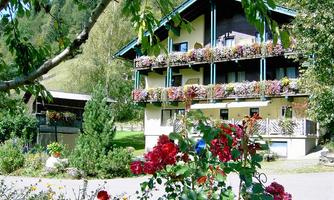 A charming building with colorful flower boxes and a well-kept garden. Surrounded by green trees and a picturesque landscape.