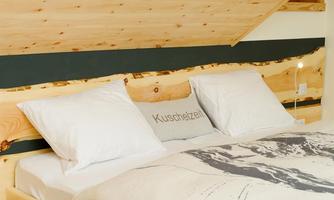A cozy bedroom with a double bed and white pillows. The wood paneling gives the room a natural atmosphere.